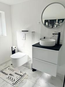 Un baño con inodoro, lavabo y espejo. en Literie d'exception, luxe calme et confort, en Rouen
