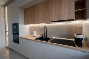 Una cocina con gabinetes blancos y un fregadero. en Vuls Apartments, en Sibiu