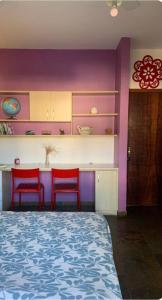 a room with two red chairs and a kitchen with purple walls at Lar dos Bem-ti-vis in Niterói