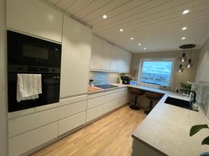 a kitchen with white cabinets and a large window at Your own room- 48 h free parking in Lillestrøm