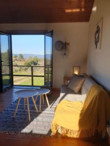a bedroom with a bed and a table and a large window at Quinta de Natureza in Nabais