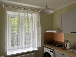 a kitchen with a window with white curtains at The 7th Apartment in Cēsis