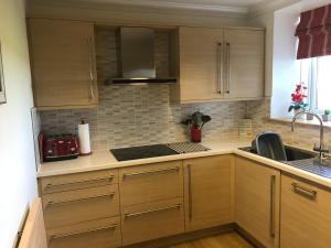 a kitchen with wooden cabinets and a sink at Converted Steading in Beach Location in Aberdeen