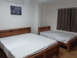 zwei Einzelbetten in einem Zimmer mit Fenster in der Unterkunft Le Sasvik in Kodaikanal