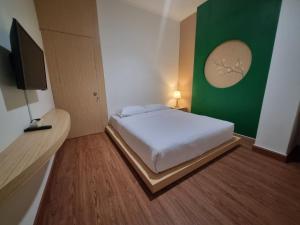 a bedroom with a white bed and a green wall at Serambi Buya Syariah 5 BR in Jetis