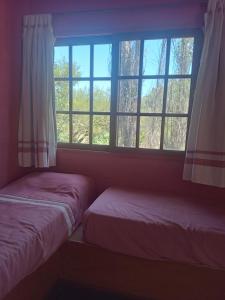 Dos camas en una habitación con ventana. en Pay huasi cabañas, en El Rincón 19 fotos más