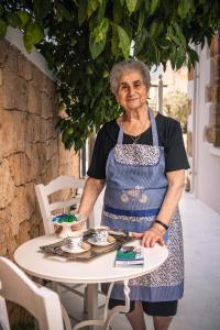 an older woman standing in front of a table at Kostis Parthenis Residence in Malia +36 photos