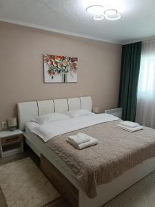 a bedroom with a large bed with two towels on it at Apartament Serenity in Băile Herculane