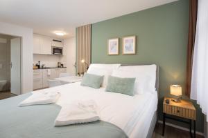 a bedroom with a large white bed and a kitchen at STAYY Nº7 Suites & Studios -Self Check-in in Zürich