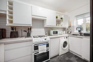 eine weiße Küche mit einem Herd und einem Geschirrspüler in der Unterkunft Quai Des Pecheurs - With Views from Bedroom Overlooking the Harbour in Poole