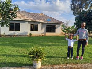 two children standing in a yard in front of a house at Arusha Serene Apartments in Arusha +2 photos