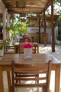 a wooden table with a vase of flowers on it at Barabara House in Jambiani