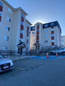 two cars parked in a parking lot in front of buildings at Departamento rosado in Puerto Montt