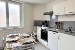 a kitchen with a table with plates on it at Le Baron du Marais - Élégant et central in Roanne