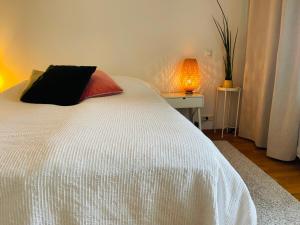 a bedroom with a white bed with a pillow and a lamp at Scandinavian design heart City Center Runeberginkatu in Helsinki