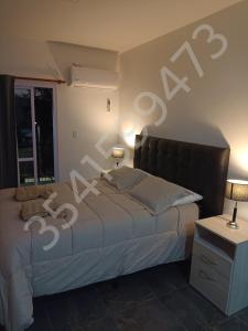 een slaapkamer met een bed, 2 lampen en een raam bij sol y brisa in La Porteña