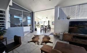 a living room with a large television and a table at La Santos Beach view Villa with 3 Bed , 3 Bath, Jacuzzi, Sea view in Mossel Bay