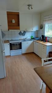 a kitchen with white appliances and a wooden floor at Gästhus i Röjdåfors in Östmark +7 photos