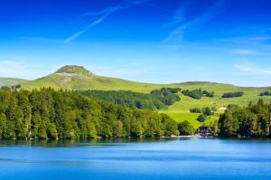 a lake with trees and a mountain in the background at Les Cimes au cœur du Massif du Sancy in Le Mont-Dore