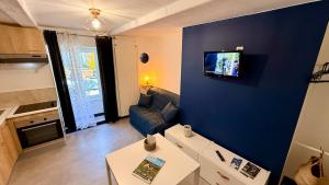 a living room with a couch and a tv on a wall at Les Cimes au cœur du Massif du Sancy in Le Mont-Dore