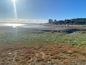 a beach with the sun shining on the water at Departamento rosado in Puerto Montt