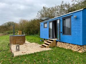 a blue tiny house with a deck and a hot tub at Maringotka pod Hrází in Drahonice