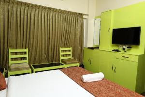 a bedroom with a white bed and a television at valparai home STAY LLHS in Vālpārai