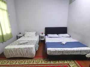 two twin beds in a room with a rug at BlackSand Guests House Langkawi in Huma