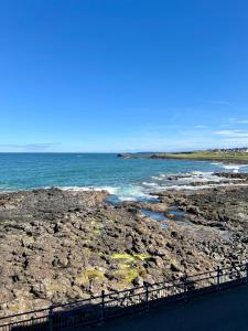 a beach with rocks and the ocean on a sunny day at 9 Atlantic Bay in Portstewart