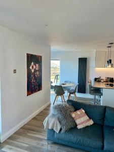 a living room with a blue couch and a kitchen at 9 Atlantic Bay in Portstewart +4 photos