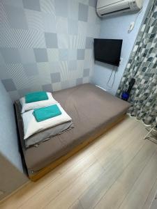 a small room with a bed and a flat screen tv at フィフティーフォージャーニー新宿戸山 in Tokyo