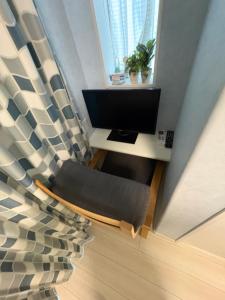a living room with a television and a chair at フィフティーフォージャーニー新宿戸山 in Tokyo