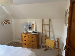Schlafzimmer mit einem Bett und einer Kommode mit einem Ventilator in der Unterkunft Little Hog Cottage, cosy seaside hideaway in Seaton