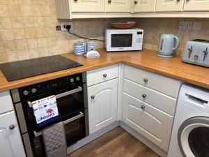 eine Küche mit weißen Schränken und einem Herd mit Backofen in der Unterkunft Little Hog Cottage, cosy seaside hideaway in Seaton + 12 Fotos