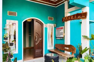 a shop with blue walls and a wooden door at Homestay Zahra Syariah Gunung Dempo Mitra RedDoorz in Lahat
