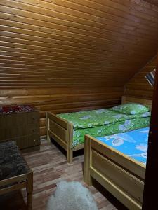 two beds in a room with wooden walls and wooden floors at Дім-Садиба Озерел in Krasna