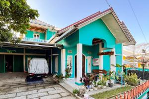 a blue and green house with a patio at Homestay Zahra Syariah Gunung Dempo Mitra RedDoorz in Lahat