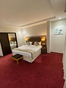 a bedroom with a large bed and a red carpet at فندق دولف الخبر in Al Khobar