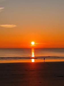 a person walking on the beach at sunset at Appartement à la mer in Saint-Hilaire-de-Riez