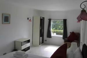 a white room with a bed and a window at The Summerhouse, Uig, Skye in Uig