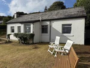 two white chairs sitting outside of a house at The Summerhouse, Uig, Skye in Uig
