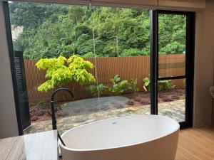 a bath tub in a room with a large window at Tambuna Retreat ,TAMBUN ,IPOH in Tambun