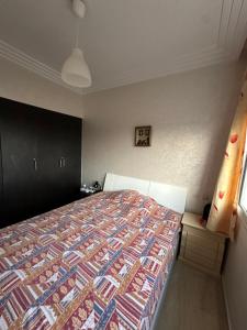ein Schlafzimmer mit einem Bett mit einer bunten Steppdecke in der Unterkunft Appartement Cosy Bord de Mer in Dar Mohammed Ould Haj Jilali