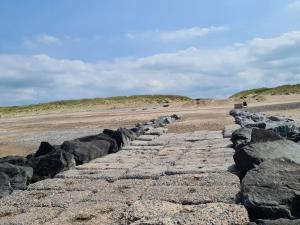 a stone path on a beach with rocks at 4 person holiday home in Lemvig-By Traum in Trans