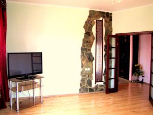 sala de estar con TV y pared de piedra. en Guest House On Abdulliny Street 54 en Almaty