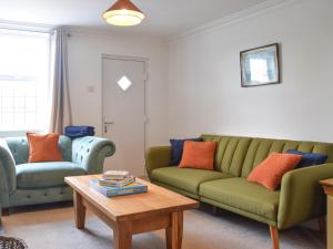 a living room with two green couches and a coffee table at Riverview Cottage in Acton