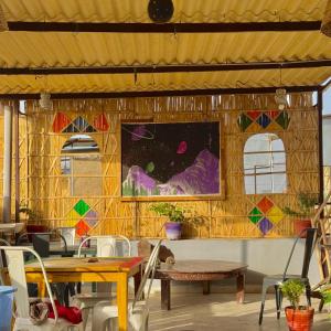a room with tables and chairs and a painting on the wall at Incredible's Hostel & Safari in Jaisalmer