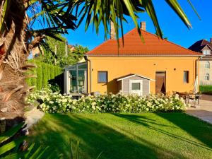a yellow house with a yard with white flowers at Füredi Virág Villa in Balatonfüred