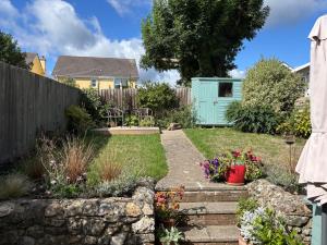 einen Garten mit einem Zaun und einem blauen Schuppen in der Unterkunft Little Hog Cottage, cosy seaside hideaway in Seaton