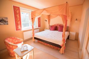 a bedroom with a canopy bed and a chair at Haus Waldesruh - Eventhotel in Schönewalde